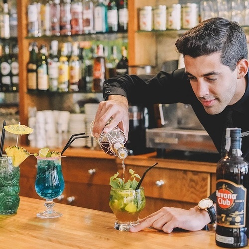 un hombre prepara un cóctel en un bar con una botella de habana club