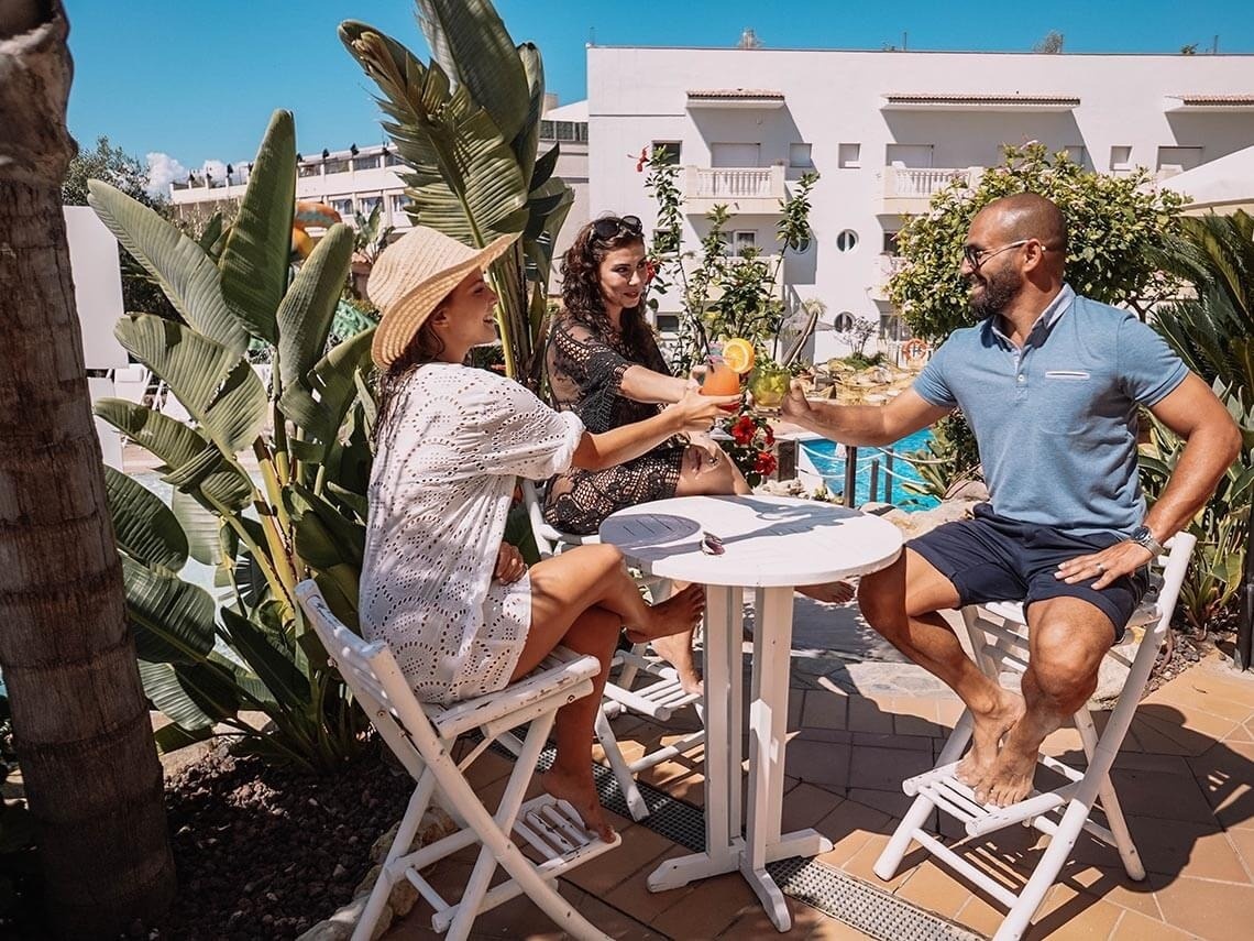 a man and two women are sitting at a table toasting with drinks