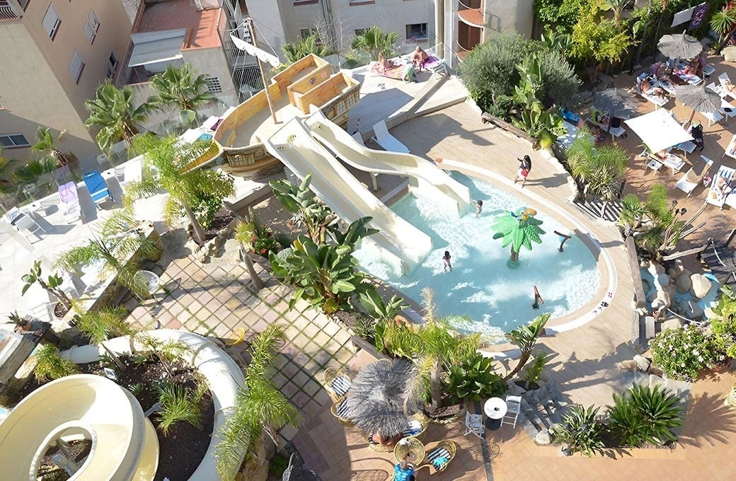 una mulher de vestido branco está ao lado de uma piscina ao pôr do sol