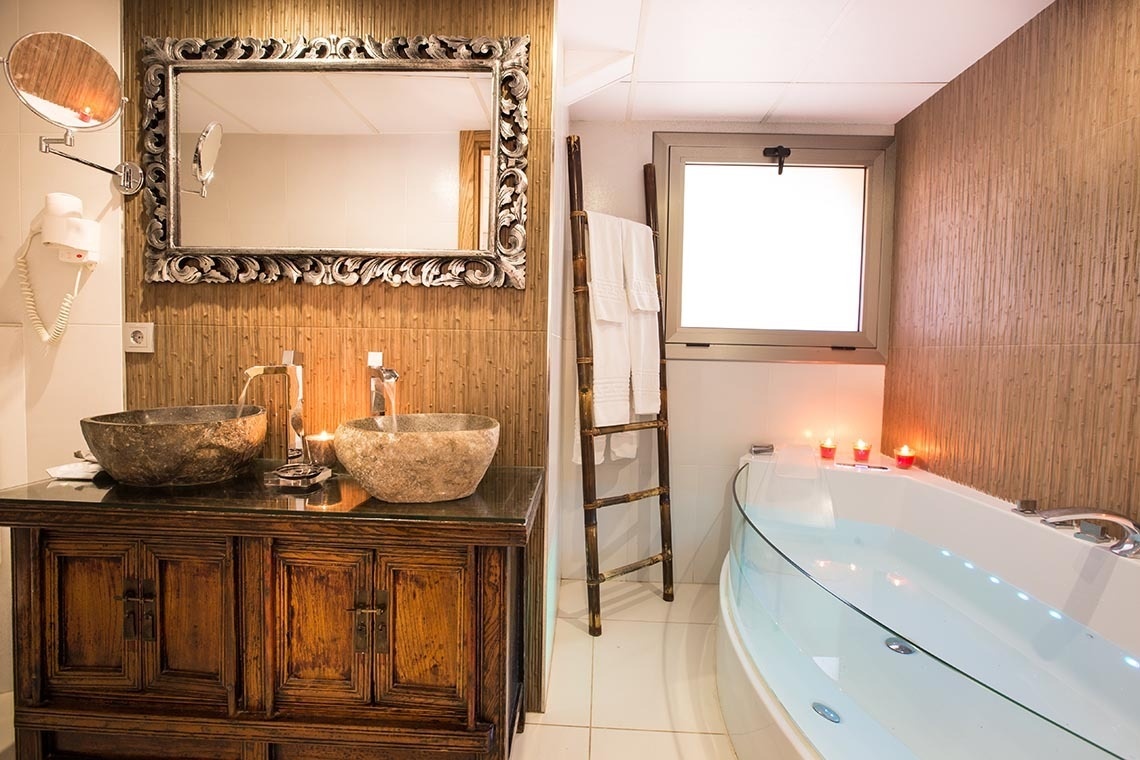 un baño con dos lavabos y una bañera con velas