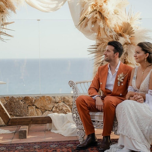 un hombre y una mujer están sentados en una silla mirando al océano