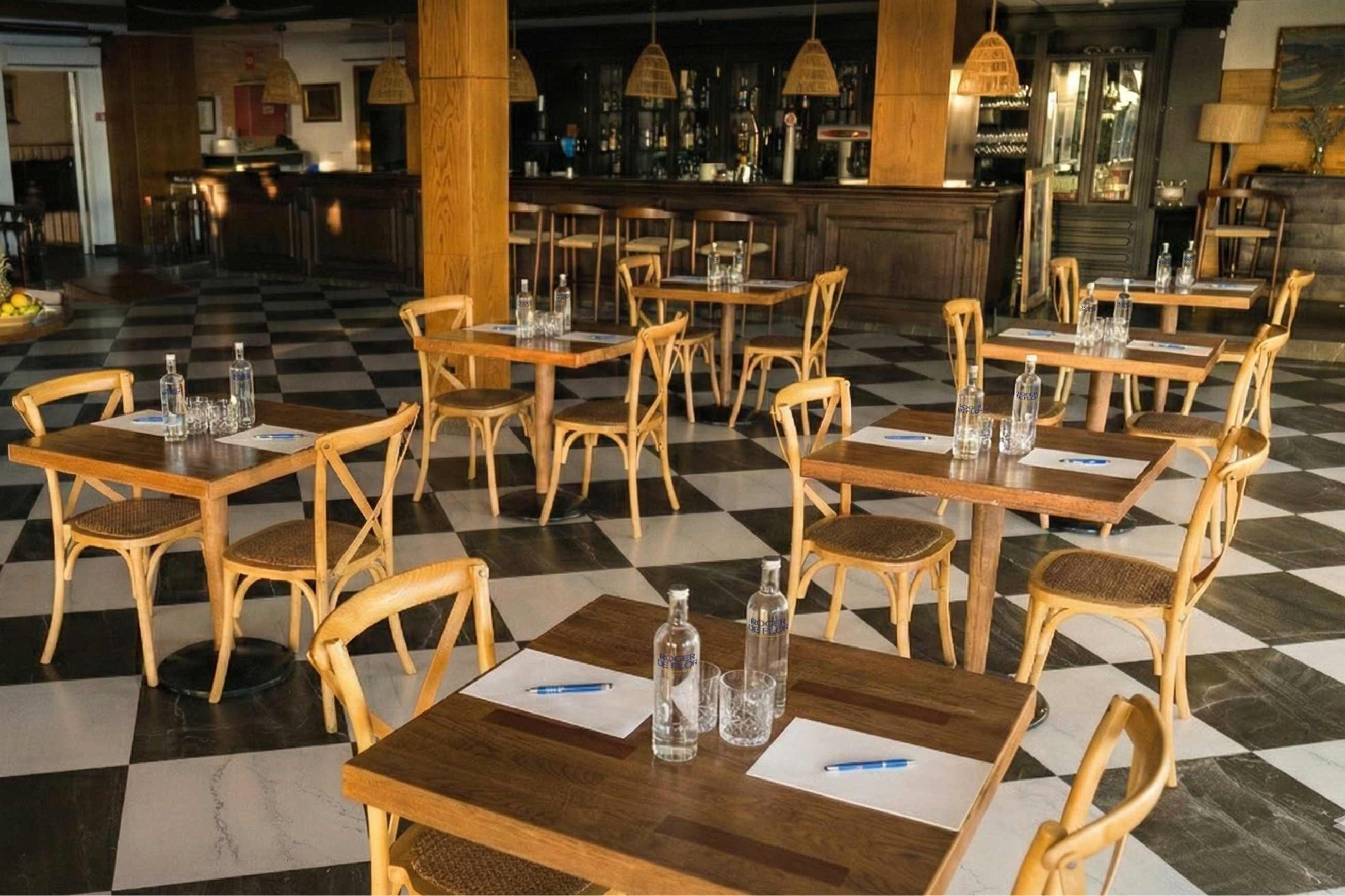 Wooden tables and chairs at Roger De Flor By Seleqtta, dining area with checkered floor.