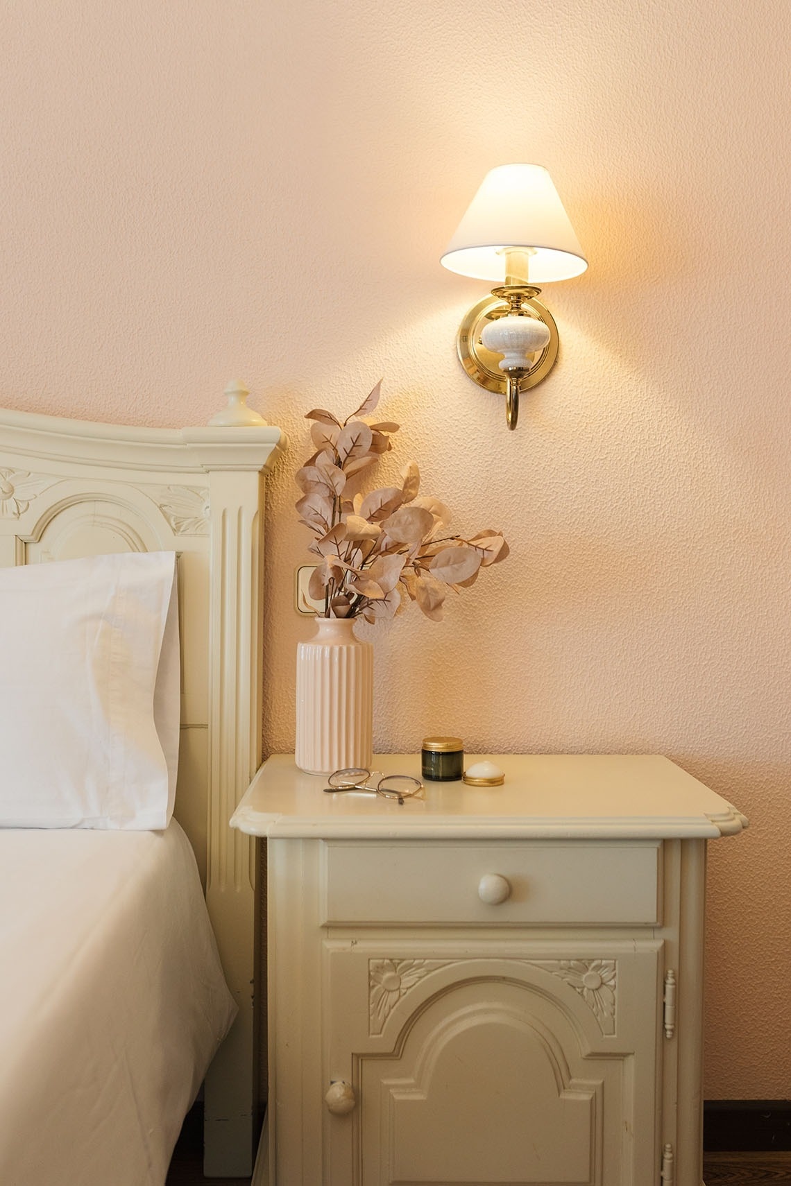 una mesita de noche con una planta en un jarrón y una lámpara