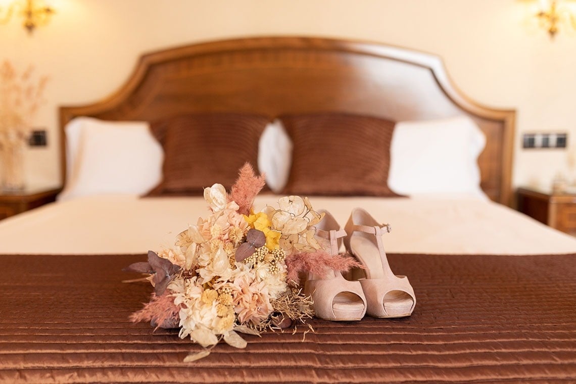un par de zapatos y un ramo de flores en una cama
