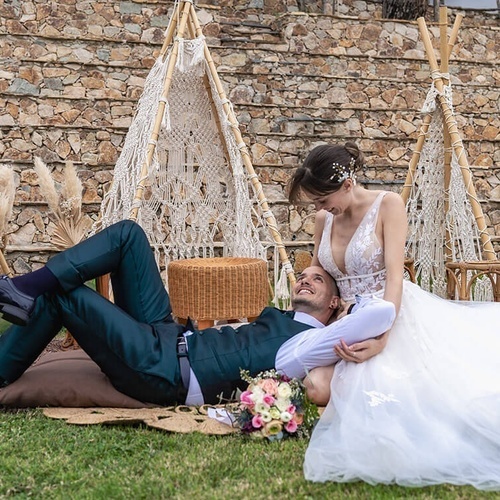 una novia y un novio acostados en la hierba frente a una tienda myzali
