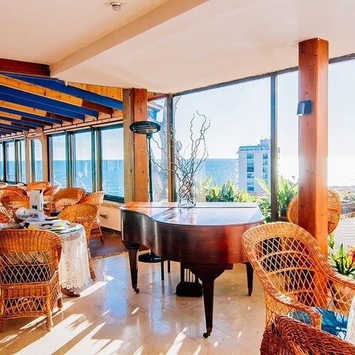 una sala de estar con un piano y sillas de mimbre