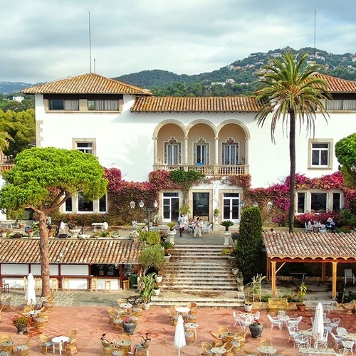 un gran edificio blanco rodeado de palmeras y mesas y sillas