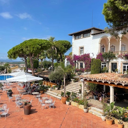 un gran edificio blanco está rodeado de mesas y sombrillas