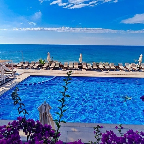 una piscina rodeada de sillas y sombrillas con vistas al océano