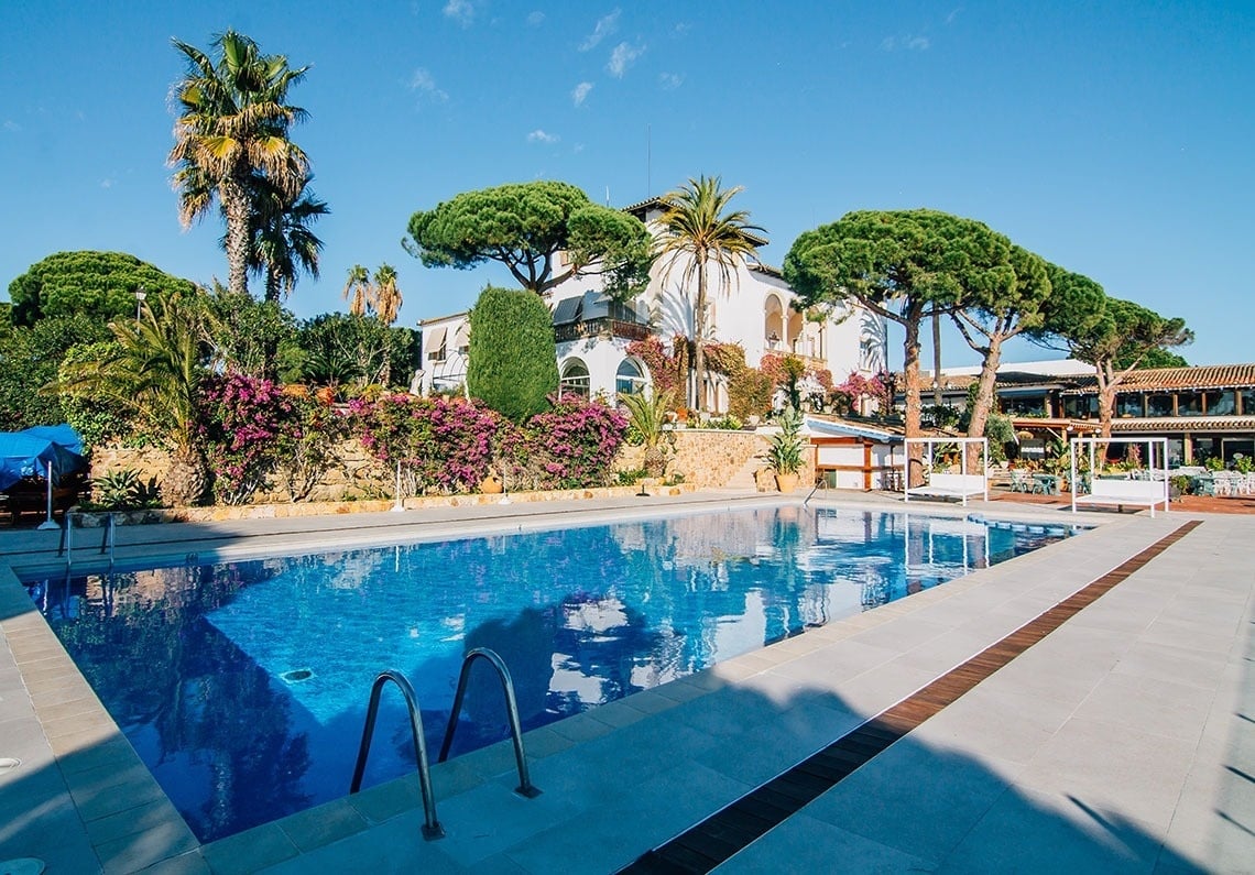 una gran piscina está rodeada de palmeras y flores