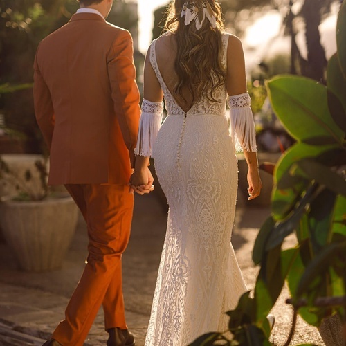 una novia y un novio caminan de la mano al atardecer