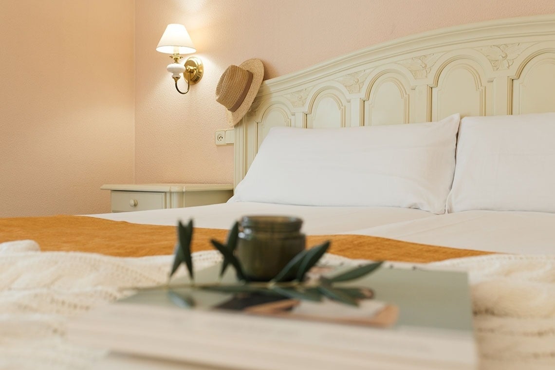 un sombrero de paja cuelga de la cabecera de una cama