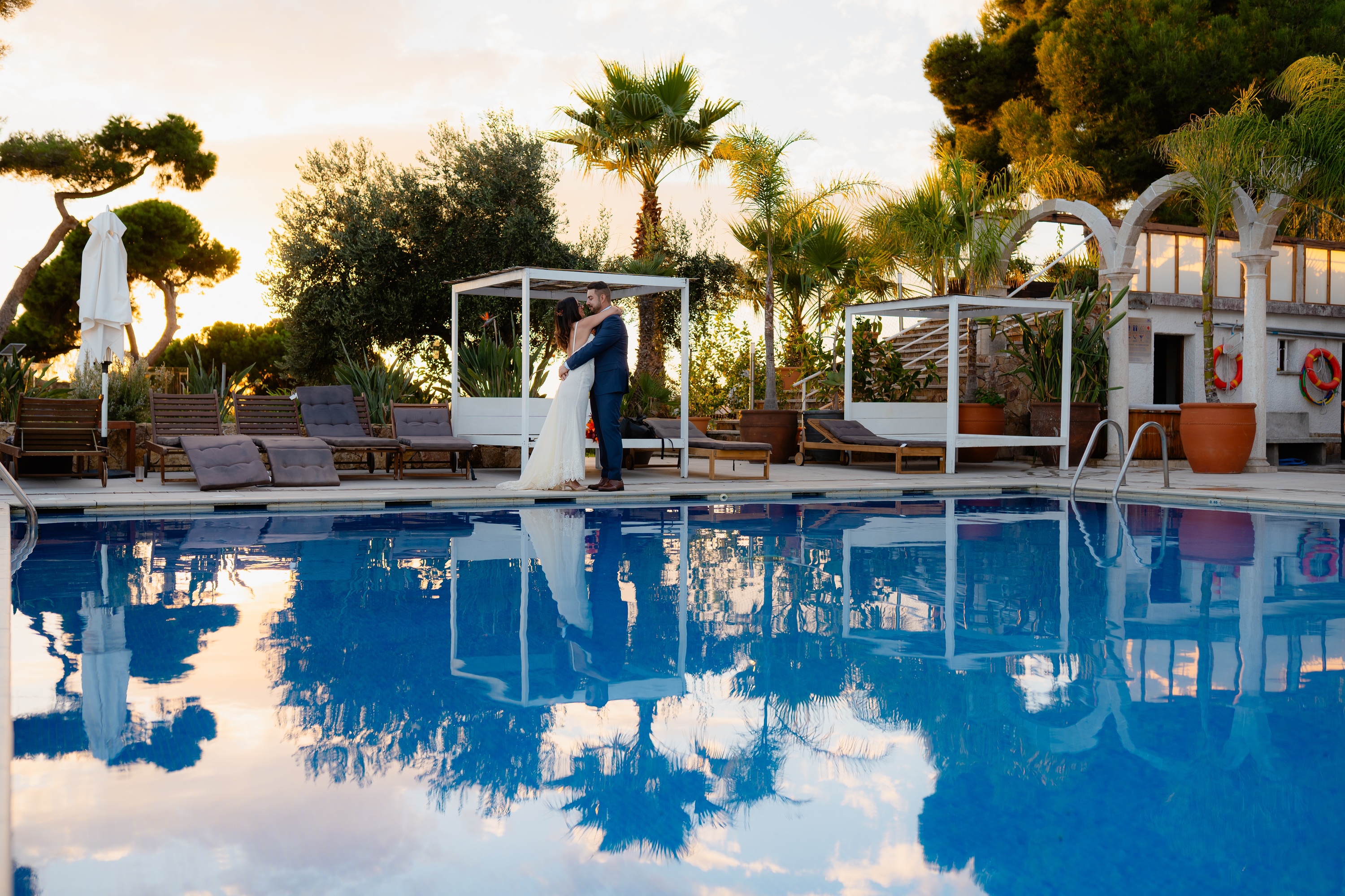 Couple embraces by pool at Roger De Flor By Seleqtta.