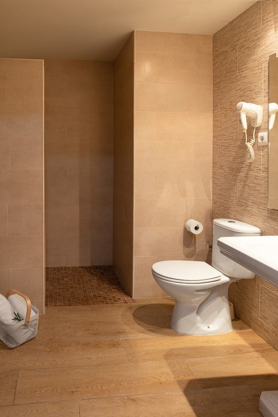 Modern hotel bathroom with shower, toilet, and sink. Roger De Flor By Seleqtta.
