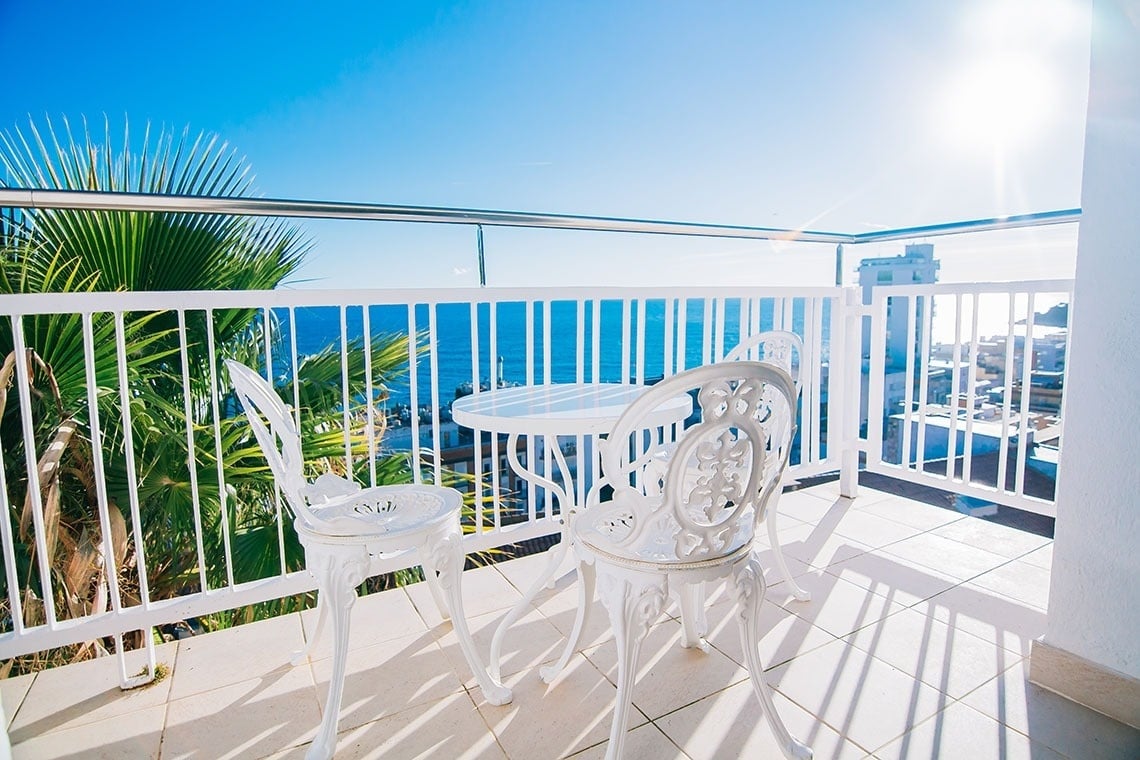 una mesa y dos sillas en un balcón con vistas al océano