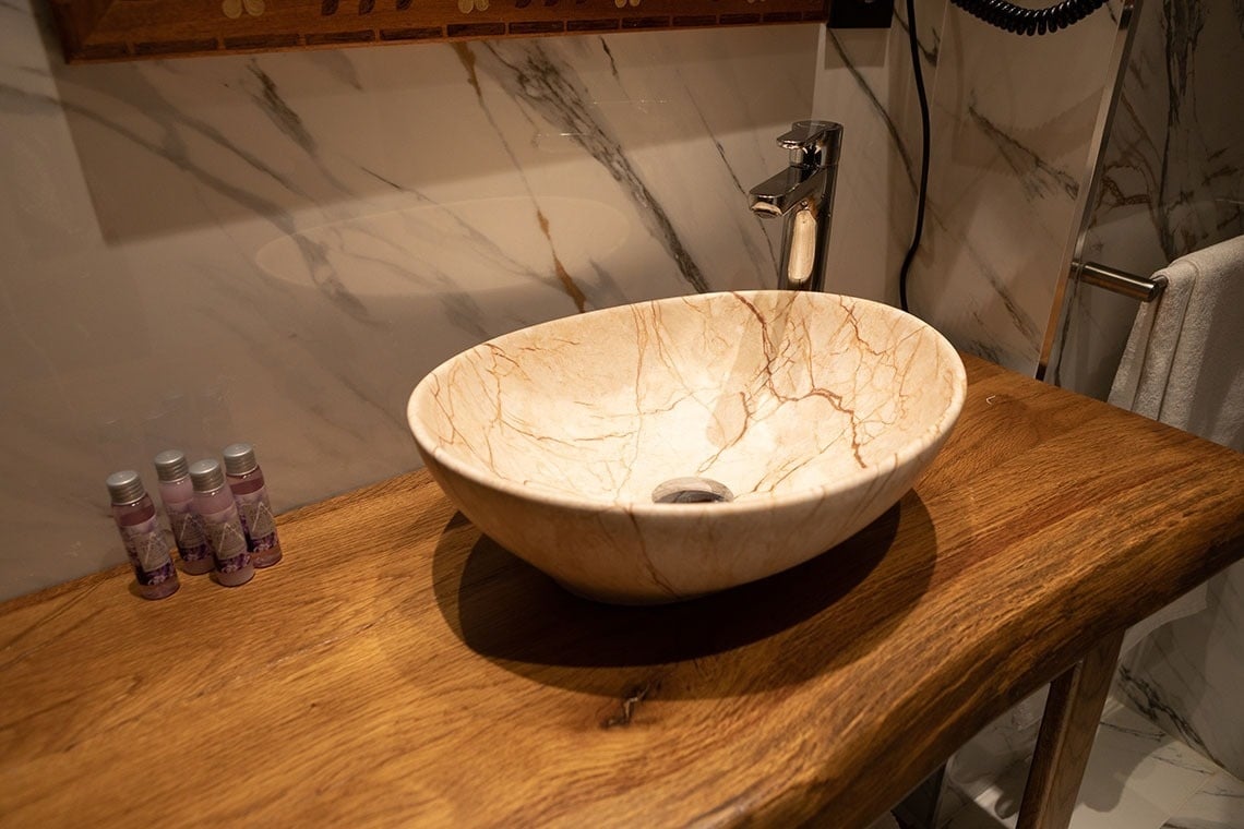 un lavabo de mármol sobre una mesa de madera en un baño