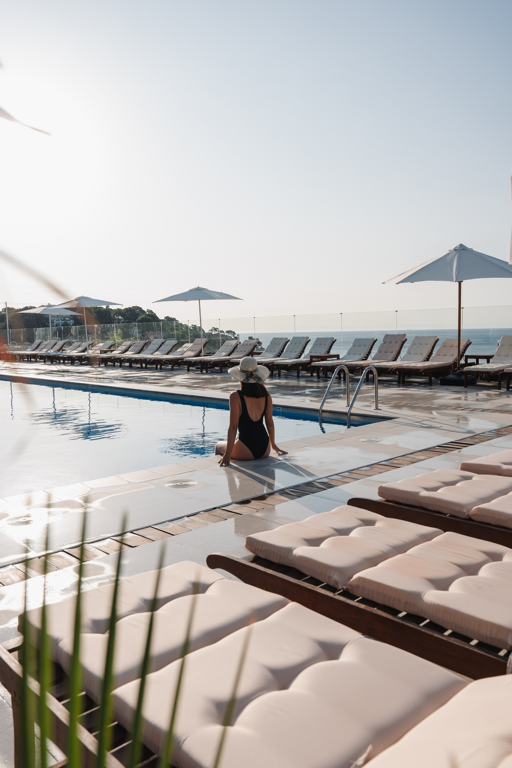 une grande piscine entourée de palmiers et de fleurs violettes