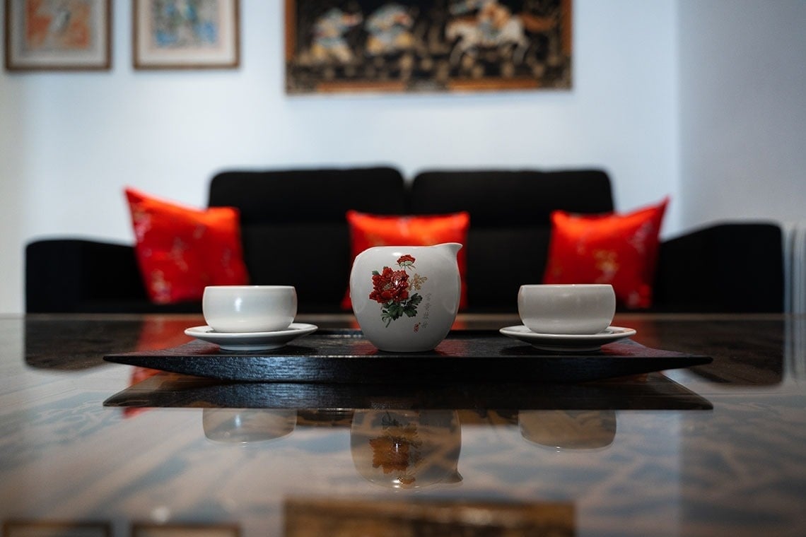 dos tazas y un jarro están sobre una mesa frente a un sofá