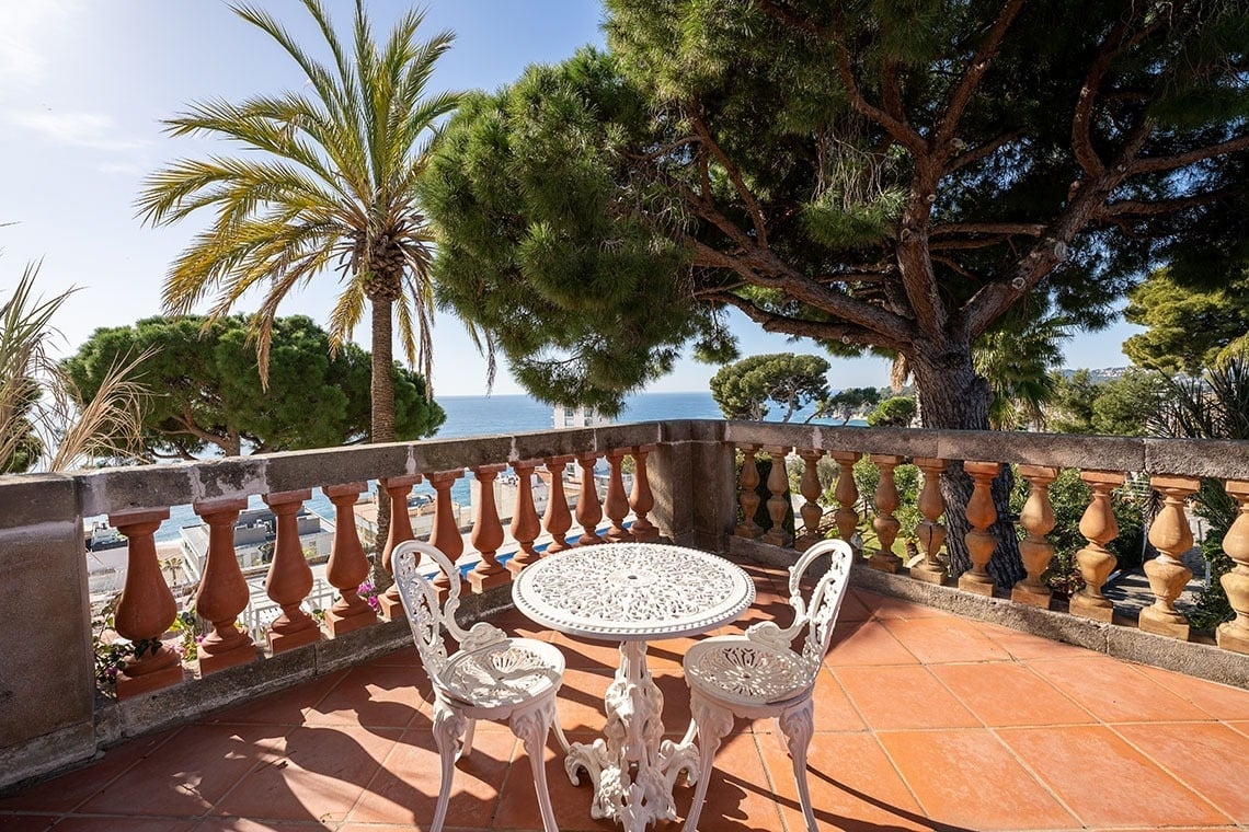 una mesa y sillas en un balcón con vistas al océano