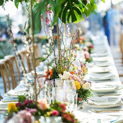 una mesa larga está decorada con platos y copas y flores