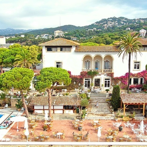 una vista aérea de un gran edificio blanco rodeado de palmeras y mesas y sillas