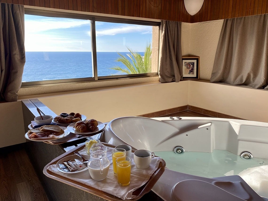 una bañera con una bandeja de comida y bebidas junto a ella