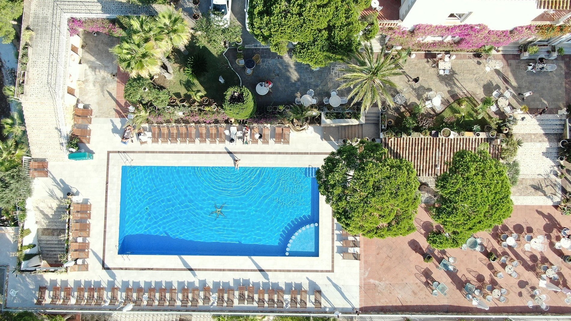 an aerial view of a large swimming pool surrounded by chairs and tables