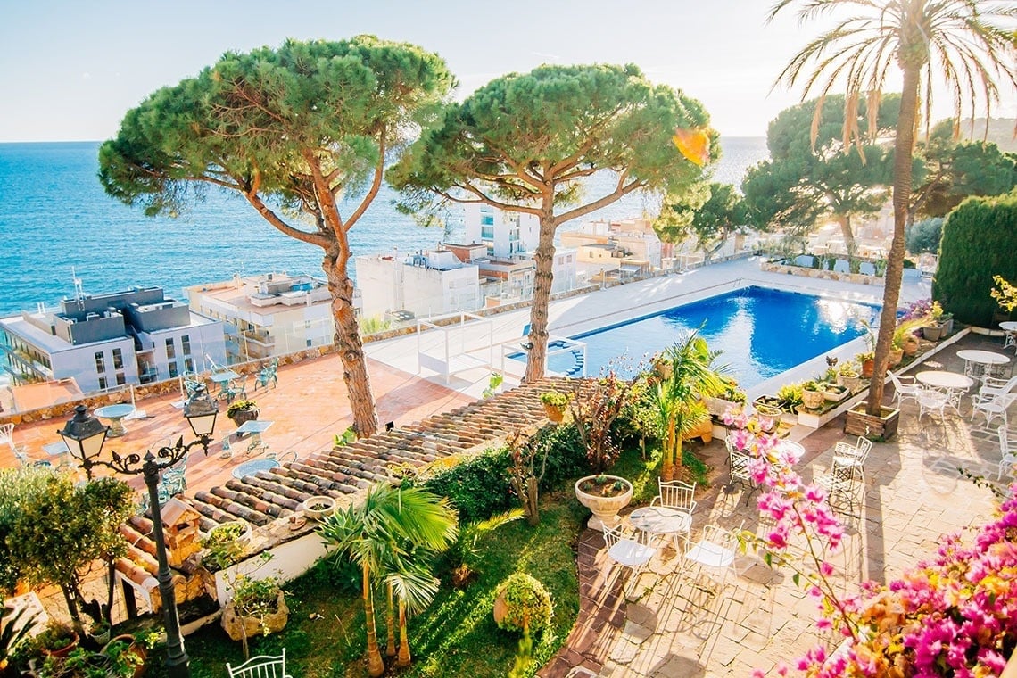 una piscina rodeada de mesas y sillas con vistas al océano