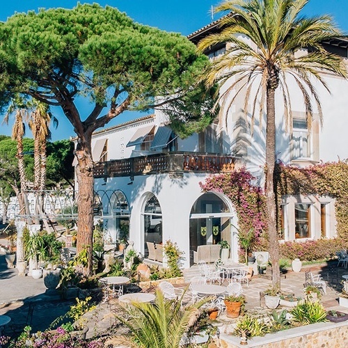 una gran casa blanca rodeada de palmeras y flores