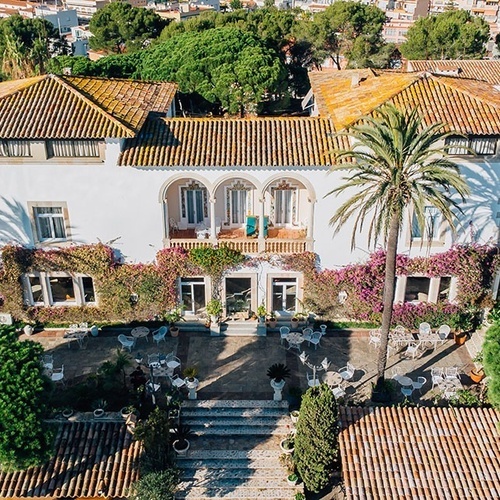 una vista aérea de una gran casa blanca rodeada de palmeras
