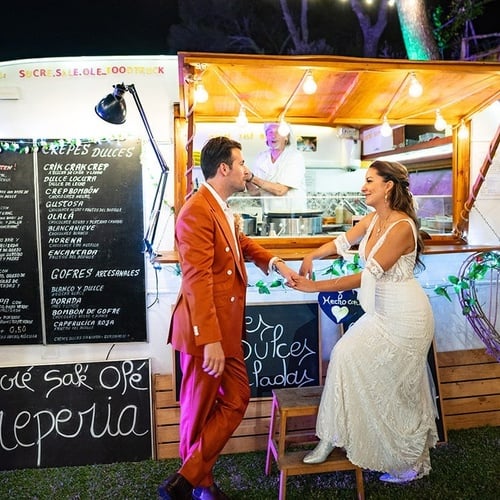 una novia y un novio se paran frente a un camión de comida que vende crepes