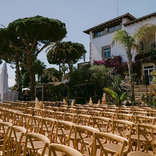 filas de sillas de madera frente a una casa blanca