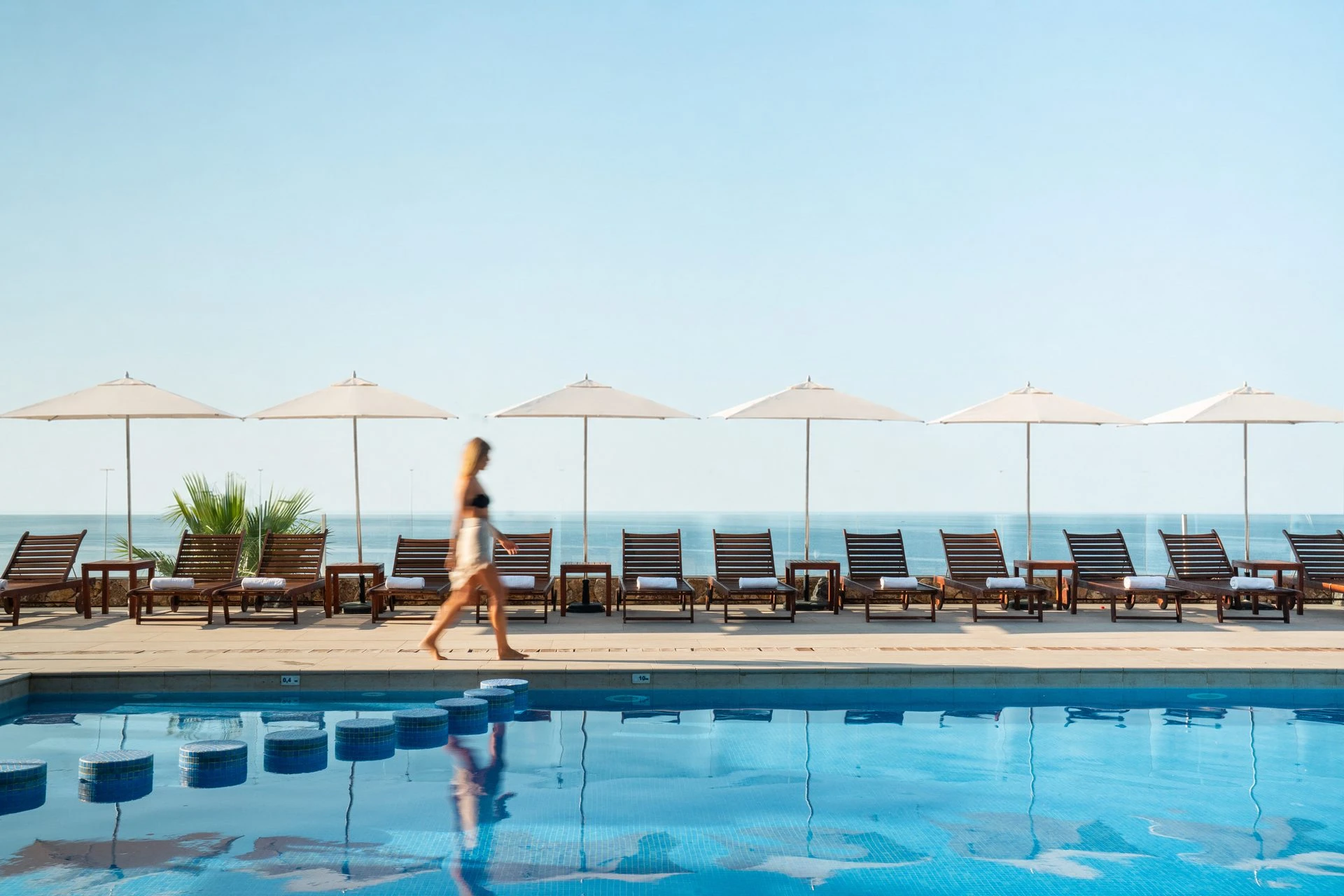 Piscina con tumbonas, sombrillas y vistas al Mediterráneo en el Hotel Roger de Flor