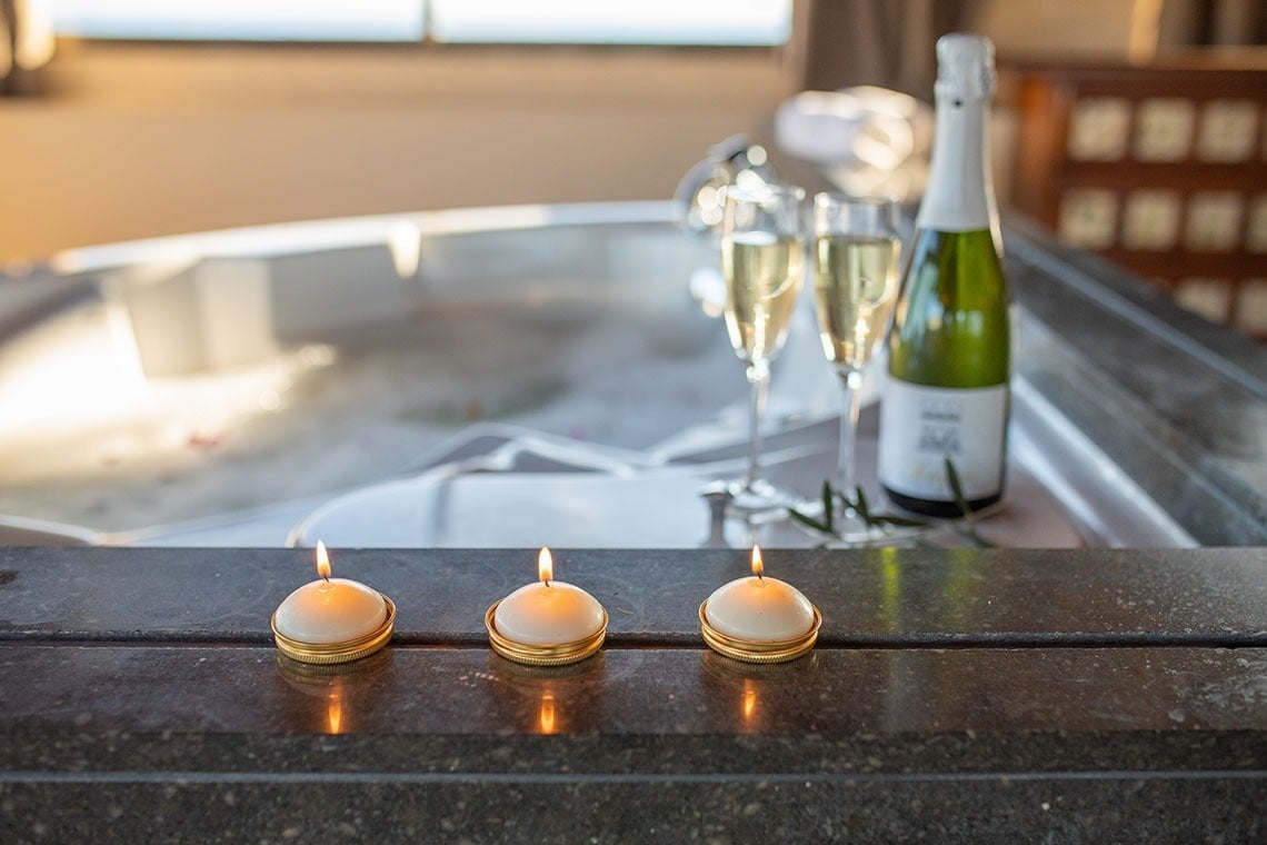 tres velas y una botella de champán junto a una bañera