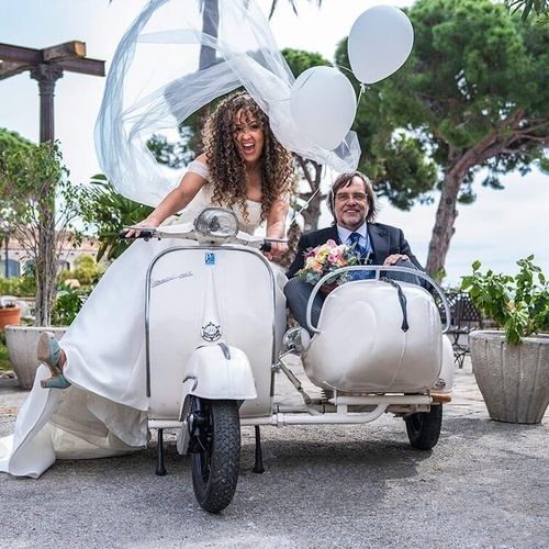 una novia y un novio en una vespa con un sidecar