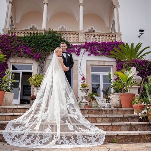 una novia y un novio posan para una foto en las escaleras de una casa