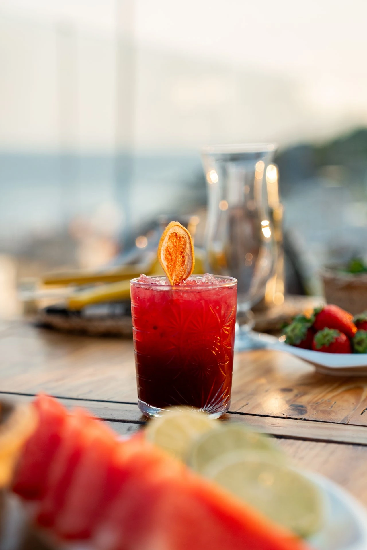 Bebida fría con rodaja de naranja deshidratada en una mesa de la terraza junto al mar