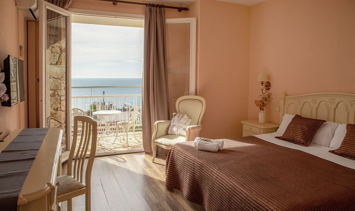 a bedroom with a large bed and a balcony overlooking the ocean