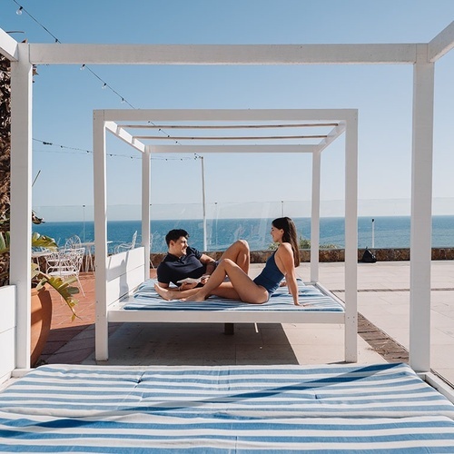 un hombre y una mujer están sentados en una cama con dosel junto a una piscina