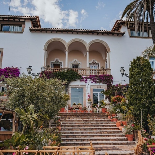 un gran edificio blanco está rodeado de plantas y flores