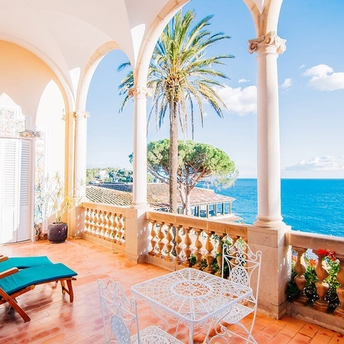 una mesa y sillas en un balcón con vistas al océano