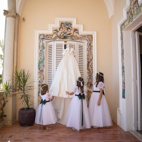 tres chicas miran un vestido de novia colgando de una ventana