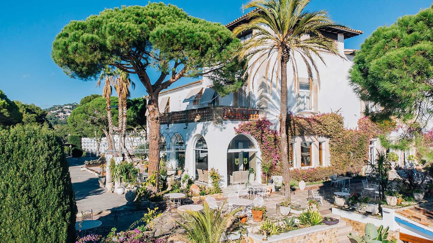 Roger De Flor By Seleqtta: white facade with balcony, garden, and palm trees.