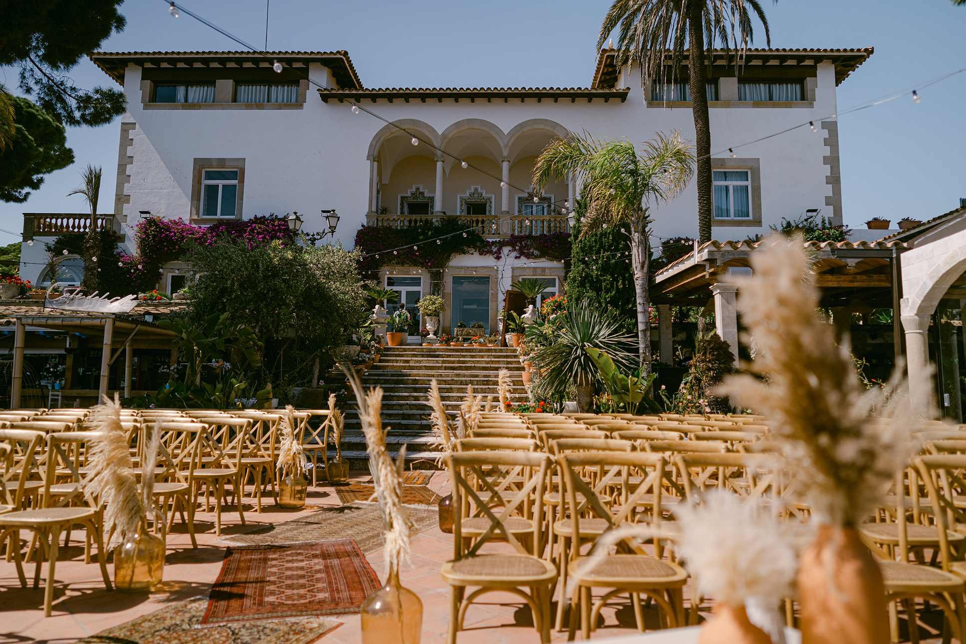 Outdoor wedding ceremony at Roger De Flor By Seleqtta with wooden chairs and rugs.