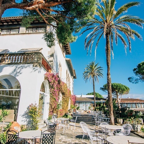 una casa blanca rodeada de palmeras y mesas y sillas