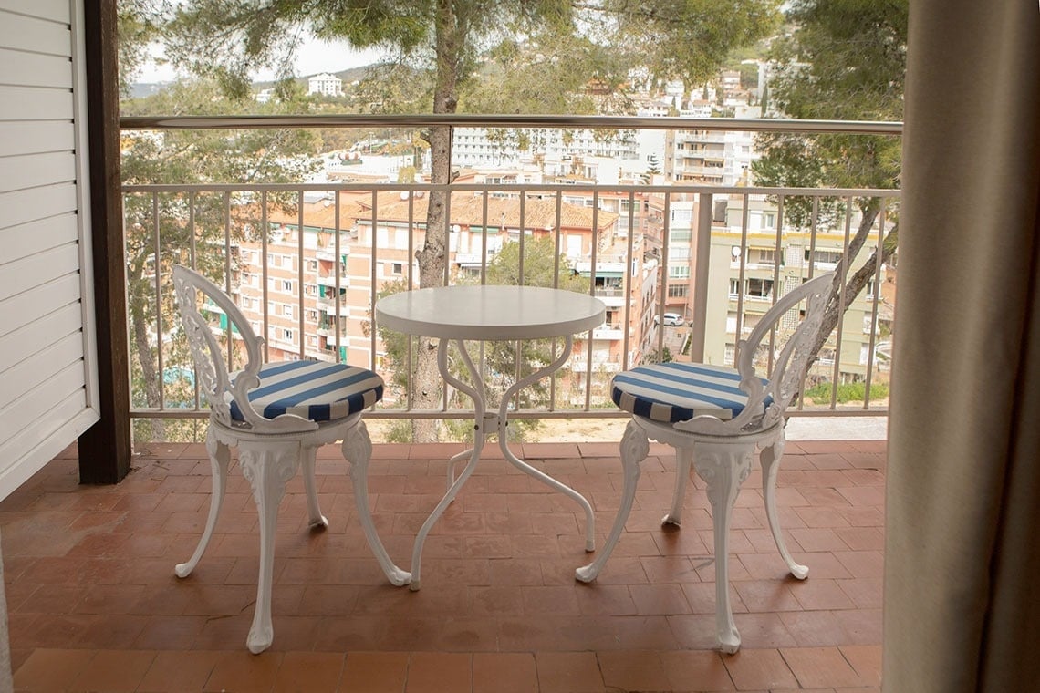 una mesa y dos sillas en un balcón con vista a la ciudad