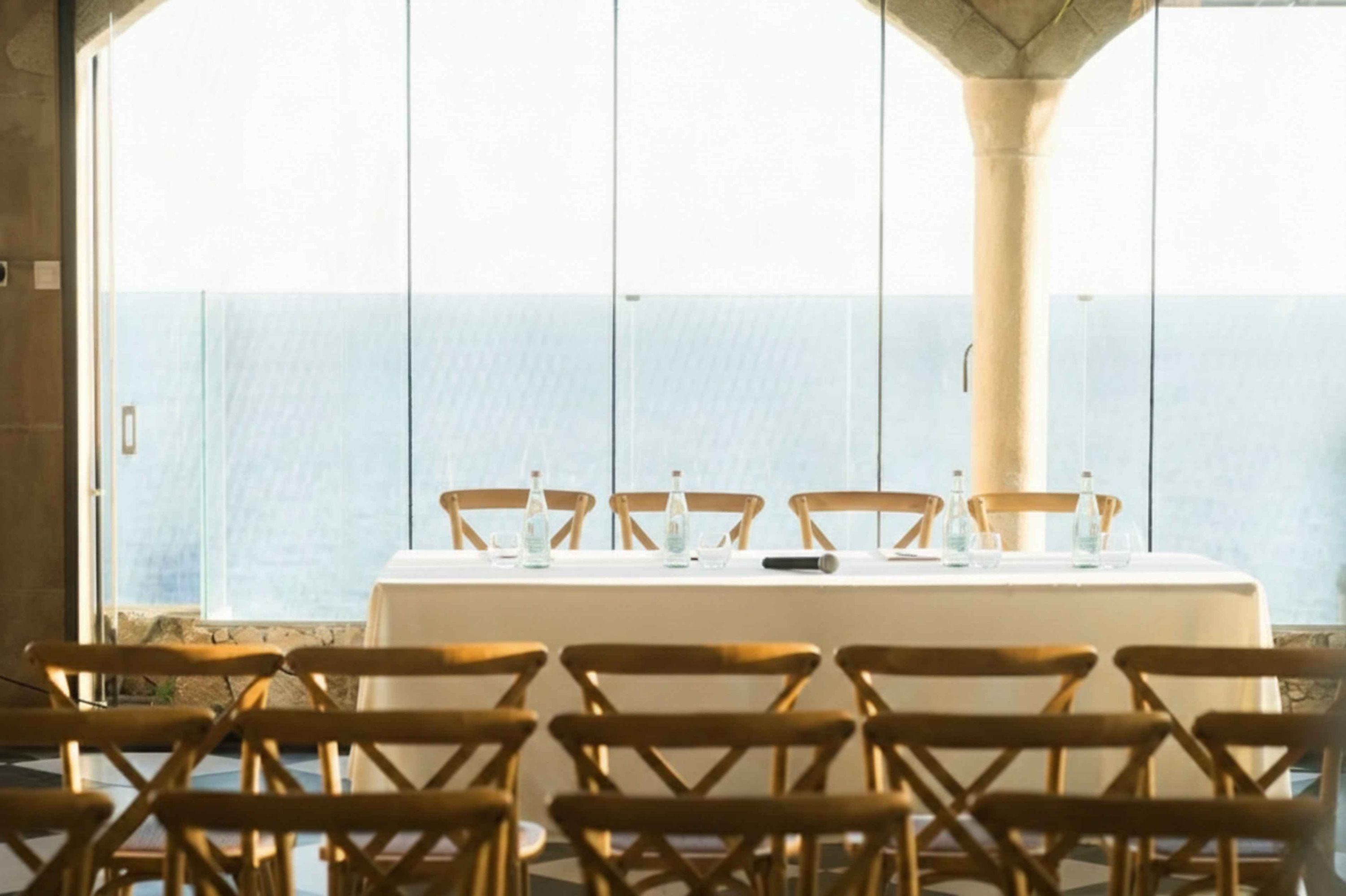 Tisch mit Stühlen und Wasserflaschen für ein Meeting im Hotel Roger De Flor By Seleqtta mit Meerblick.