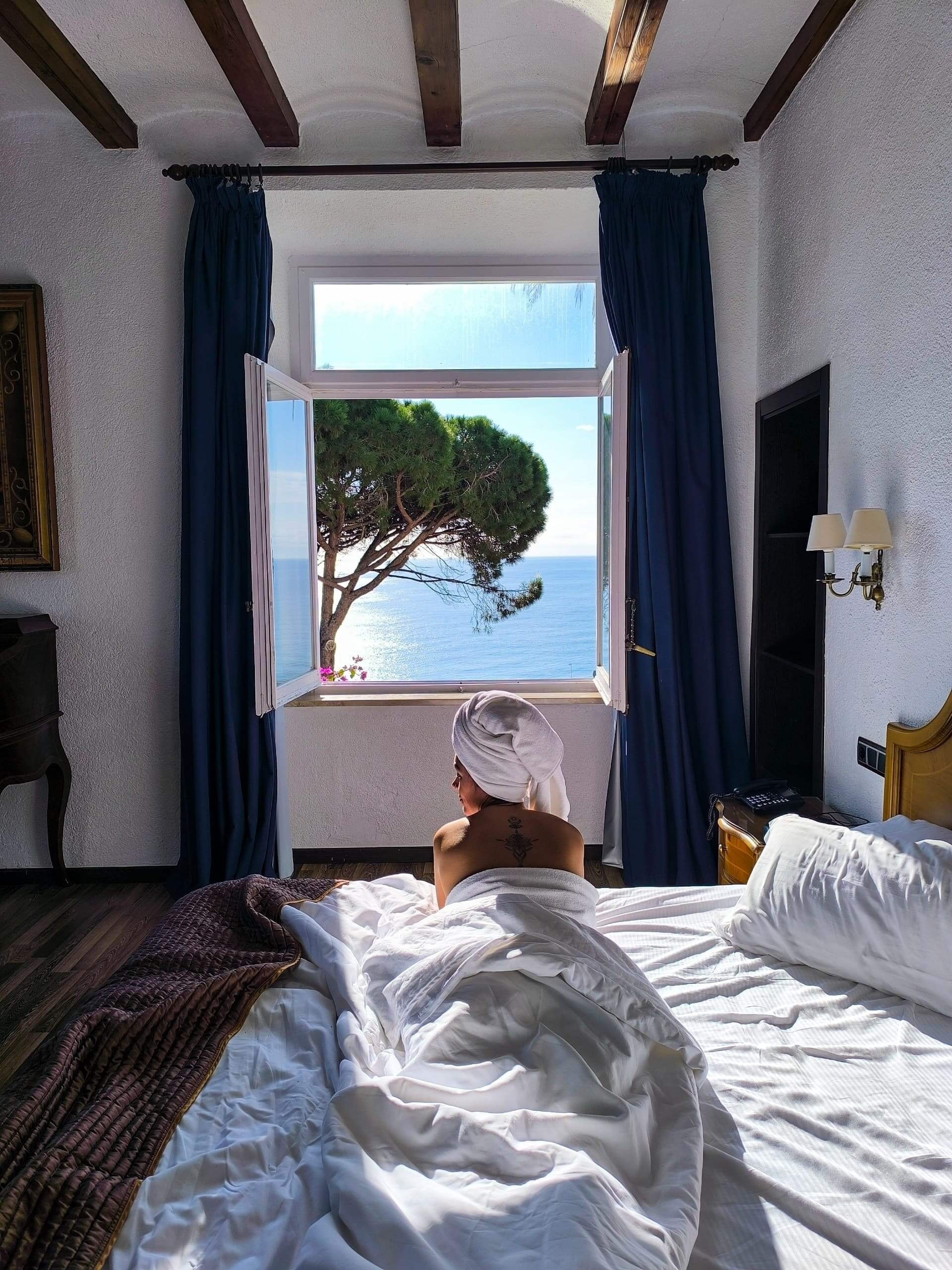 une femme en robe se tient sur un balcon avec vue sur l' océan
