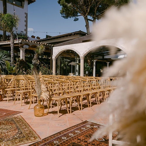 una fila de sillas de madera están dispuestas para una ceremonia de boda al aire libre