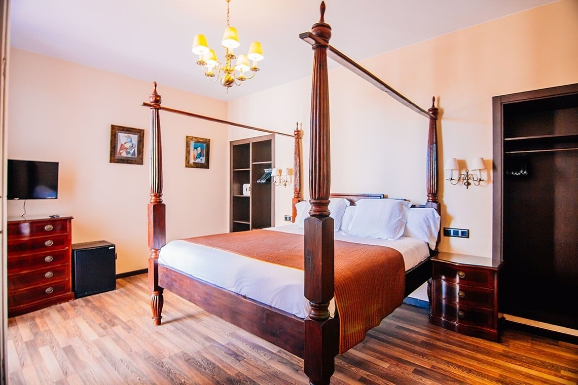 una habitación con una cama de cuatro postes y una televisión